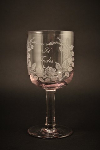 Gammelt erindrings glas fra Holmegaard glasværk med 
fine graveret blomster dekorationer og skrift "Til Fader"
H:16,5cm. Dia:7,5cm.