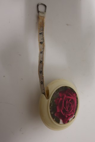 Measuring tool in a round holder, the holder is with a rose decoratedThe measuring tape is pulled out from the box and let in againText: "Dean Measure" Made in England